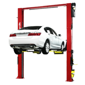 A white car is parked in the back of a red two post lift.