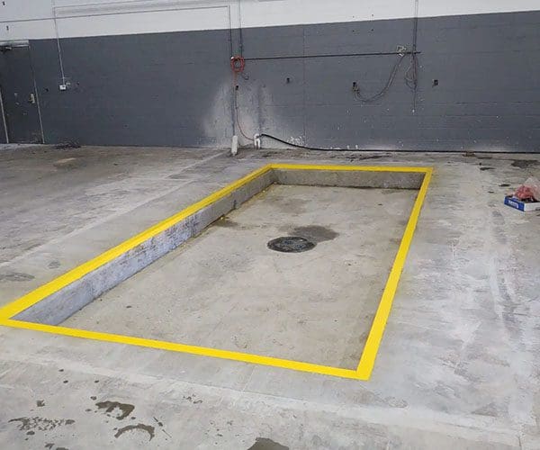 Empty concrete area marked with yellow lines and drain in the center.