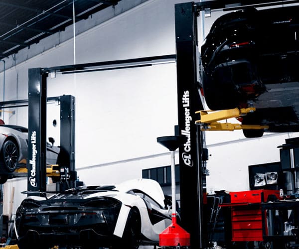 Car lifted on a hydraulic lift in a garage workshop.